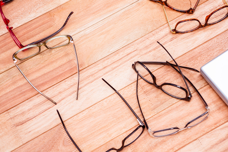 Różne okulary korekcyjne ułożone na drewnianym stole - optyka, wzrok i dobór okularów.