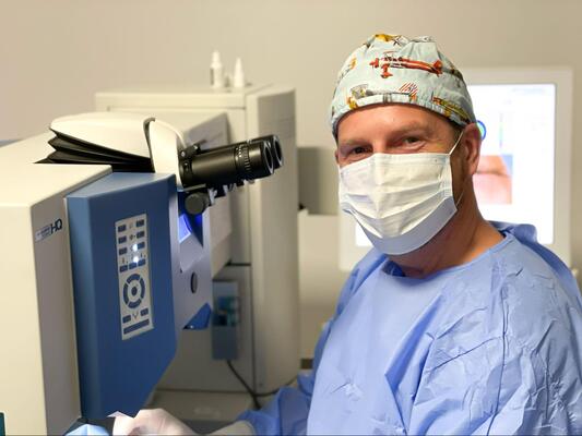 Idealny Wzrok – twarde zobowiązanie Chirurg okulista w stroju operacyjnym przy laserze okulistycznym podczas zabiegu korekcji wzroku